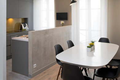 Cette image montre une salle à manger ouverte sur la cuisine design avec un mur gris et un sol marron.