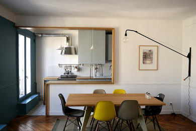 Idée de décoration pour une salle à manger ouverte sur la cuisine design de taille moyenne avec un mur blanc et un sol en bois brun.