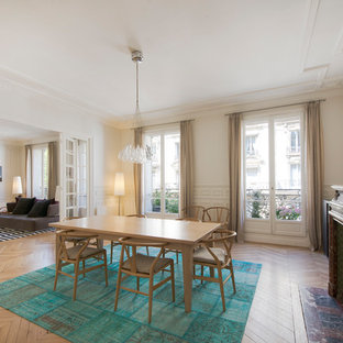 Cette image montre une grand salle à manger ouverte sur le salon traditionnelle avec un mur blanc, une cheminée standard, un sol marron, un sol en bois clair et un manteau de cheminée en pierre.