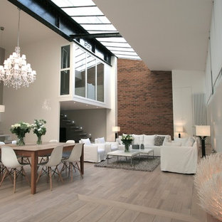 Cette photo montre une grand salle à manger ouverte sur le salon tendance avec un mur multicolore, un sol en bois clair et aucune cheminée.