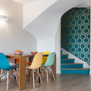 Cette photo montre une salle à manger ouverte sur le salon rétro de taille moyenne avec un mur blanc et un sol en bois clair.