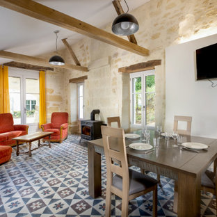 Inspiration pour une salle à manger ouverte sur le salon rustique avec un mur blanc, un sol multicolore et un plafond voûté.