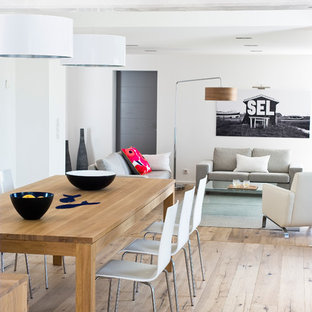 Cette image montre une grand salle à manger ouverte sur le salon marine avec un mur blanc, un sol en bois clair et aucune cheminée.
