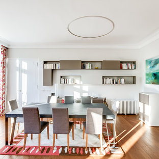 Aménagement d'une grand salle à manger contemporaine fermée avec un mur blanc, un sol en bois brun et aucune cheminée.
