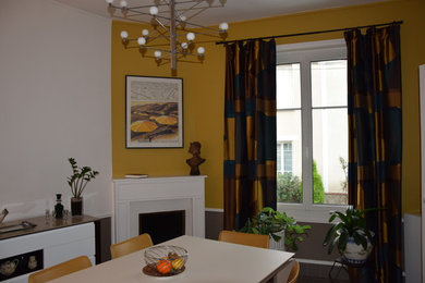 Réalisation d'une salle à manger tradition avec un mur jaune, une cheminée d'angle, un manteau de cheminée en bois et un sol gris.