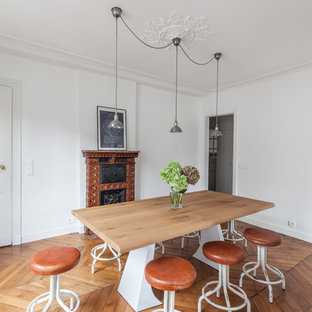 Cette photo montre une salle à manger tendance fermée et de taille moyenne avec un mur blanc, une cheminée standard et un sol en bois brun.