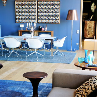 Exemple d'une salle à manger ouverte sur le salon tendance de taille moyenne avec un mur bleu et un sol en bois clair.
