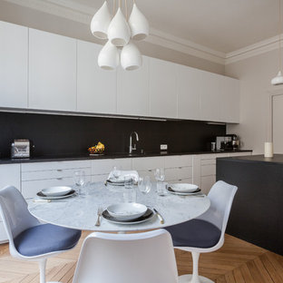 Exemple d'une salle à manger ouverte sur la cuisine tendance de taille moyenne avec un mur blanc et un sol en bois brun.