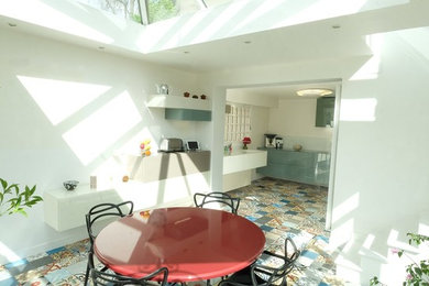 Cette image montre une salle à manger ouverte sur le salon design de taille moyenne avec un mur blanc, un sol en carrelage de céramique, aucune cheminée et un sol multicolore.