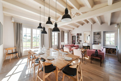 Cette photo montre une grande salle à manger ouverte sur le salon scandinave avec un mur blanc, un sol en bois brun et éclairage.