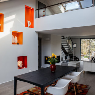 Exemple d'une salle à manger ouverte sur le salon éclectique de taille moyenne avec un mur gris, un manteau de cheminée en plâtre, un sol gris et une cheminée double-face.