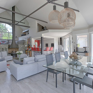 Exemple d'une salle à manger ouverte sur le salon tendance avec un sol en bois clair et un sol gris.