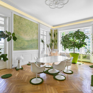 Inspiration pour une salle à manger design avec un mur vert, un sol en bois brun, une cheminée standard, un manteau de cheminée en pierre et un sol marron.