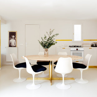 Cette image montre une grand salle à manger ouverte sur la cuisine design avec un mur blanc et un sol blanc.