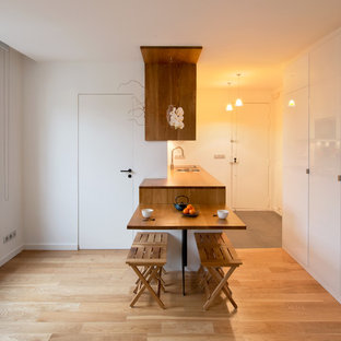 Cette photo montre une petit salle à manger ouverte sur la cuisine tendance avec un mur blanc, un sol en bois clair et aucune cheminée.