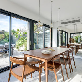 Exemple d'une salle à manger tendance fermée avec un mur blanc et un sol gris.