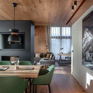 Réalisation d'une salle à manger chalet avec un mur blanc, un sol en bois brun, une cheminée double-face et un sol marron.