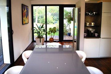 Imagen de comedor actual grande abierto con suelo de bambú, paredes blancas y suelo marrón