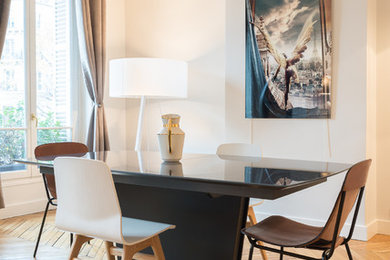 Cette image montre une salle à manger ouverte sur le salon design de taille moyenne avec un sol en bois brun et un mur blanc.