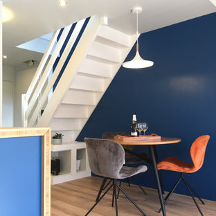 Réalisation d'une petit salle à manger ouverte sur le salon design avec un mur bleu, un sol en bois clair et un sol beige.