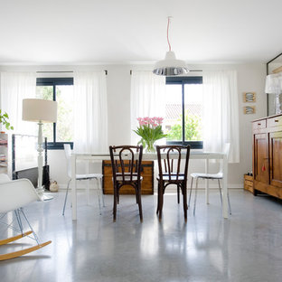 Cette photo montre une salle à manger tendance avec un mur blanc et béton au sol.