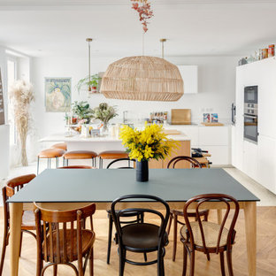 Exemple d'une salle à manger ouverte sur la cuisine scandinave de taille moyenne avec un mur blanc, un sol en bois brun et un sol marron.