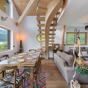 Cette image montre une salle à manger ouverte sur le salon chalet avec un mur blanc, un sol en bois clair et aucune cheminée.