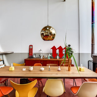 Cette photo montre une salle à manger ouverte sur le salon éclectique de taille moyenne avec un mur multicolore, un manteau de cheminée en métal et un sol rouge.