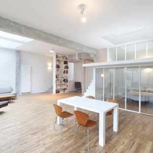 Idées déco pour une grand salle à manger ouverte sur le salon moderne avec un mur blanc et un sol en bois clair.