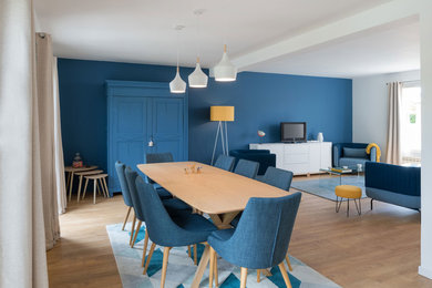 Aménagement d'une grande salle à manger ouverte sur le salon scandinave avec un mur bleu, parquet clair et aucune cheminée.