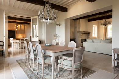 Aménagement d'une salle à manger romantique avec un mur beige, un sol en travertin, une cheminée standard, un manteau de cheminée en pierre et un sol beige.