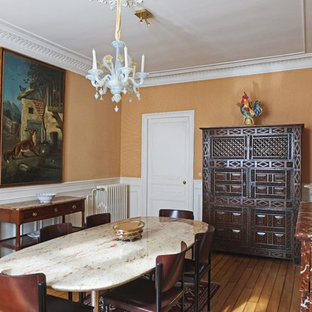 Bild på en mellanstor vintage separat matplats, med orange väggar, mellanmörkt trägolv, en standard öppen spis och en spiselkrans i sten