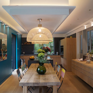Idée de décoration pour une salle à manger ouverte sur la cuisine design de taille moyenne avec un mur bleu, un sol en bois clair et aucune cheminée.