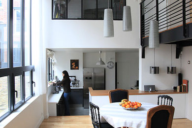 Réalisation d'une salle à manger ouverte sur la cuisine design de taille moyenne avec un mur blanc et un sol en bois brun.