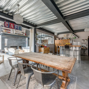 Cette photo montre une grand salle à manger ouverte sur le salon industrielle avec un mur gris et béton au sol.