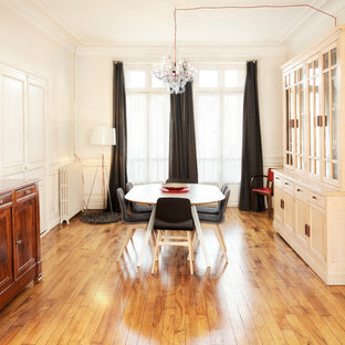 Aménagement d'une grand salle à manger classique fermée avec un mur beige, un sol en bois brun, un sol beige, une cheminée standard et un manteau de cheminée en pierre.