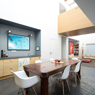 Idées déco pour une grand salle à manger ouverte sur le salon contemporaine avec un mur blanc, béton au sol, aucune cheminée et un sol noir.