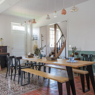Idée de décoration pour une salle à manger champêtre avec un mur blanc et un sol rouge.