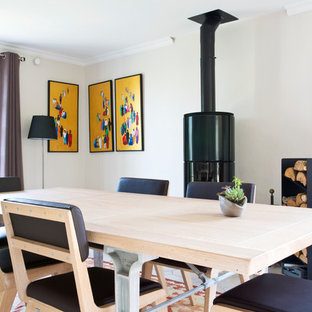 Cette image montre une salle à manger rustique fermée avec un mur beige et un poêle à bois.