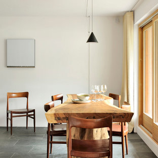 Réalisation d'une salle à manger ouverte sur la cuisine chalet avec un mur blanc et un sol noir.