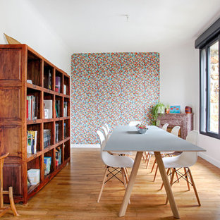 Exemple d'une salle à manger tendance fermée et de taille moyenne avec un mur orange, une cheminée standard, un manteau de cheminée en pierre et un sol en bois brun.