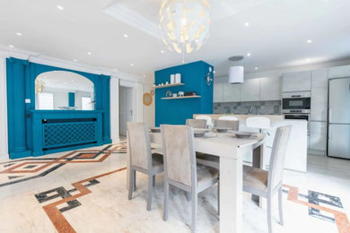Cette photo montre une grande salle à manger ouverte sur le salon tendance avec un mur bleu, un sol en marbre, une cheminée standard, un manteau de cheminée en bois, un sol blanc, un plafond à caissons et boiseries.