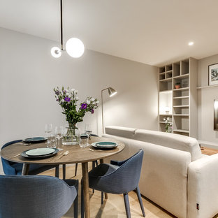Cette photo montre une salle à manger ouverte sur le salon tendance de taille moyenne avec un mur gris, un sol en bois clair et aucune cheminée.