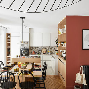 Aménagement d'une salle à manger ouverte sur le salon scandinave avec un mur rouge, un sol en bois brun et un sol marron.