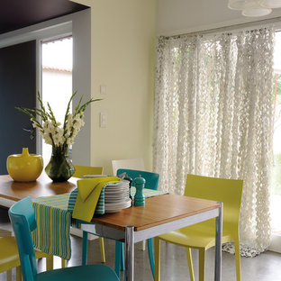 Idées déco pour une salle à manger ouverte sur le salon contemporaine de taille moyenne avec un mur jaune et béton au sol.