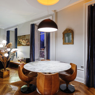Idée de décoration pour une salle à manger ouverte sur le salon bohème de taille moyenne avec un mur gris, un sol en bois brun et aucune cheminée.