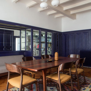 Cette photo montre une grand salle à manger éclectique fermée avec un mur bleu, un sol en bois brun, un sol marron et boiseries.