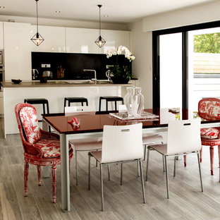 Idée de décoration pour une salle à manger ouverte sur la cuisine design de taille moyenne avec un mur blanc et un sol en bois clair.