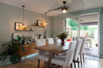 Cette photo montre une salle à manger ouverte sur le salon scandinave de taille moyenne avec un mur vert, parquet clair, un poêle à bois, un manteau de cheminée en métal et du papier peint.