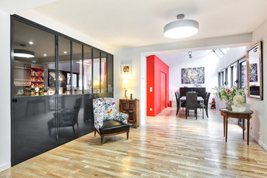 Réalisation d'une salle à manger ouverte sur le salon design de taille moyenne avec un mur rouge, parquet clair, un poêle à bois et un manteau de cheminée en métal.